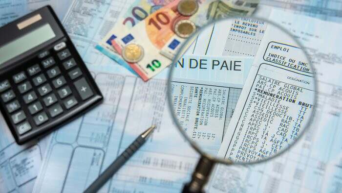 Bulletin de paie français à la loupe, avec argent en euros, calculette et stylo
